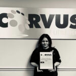 Corvus of Little Rock Franchisee Laura Torres - Black & White photo standing in front of Corvus sign